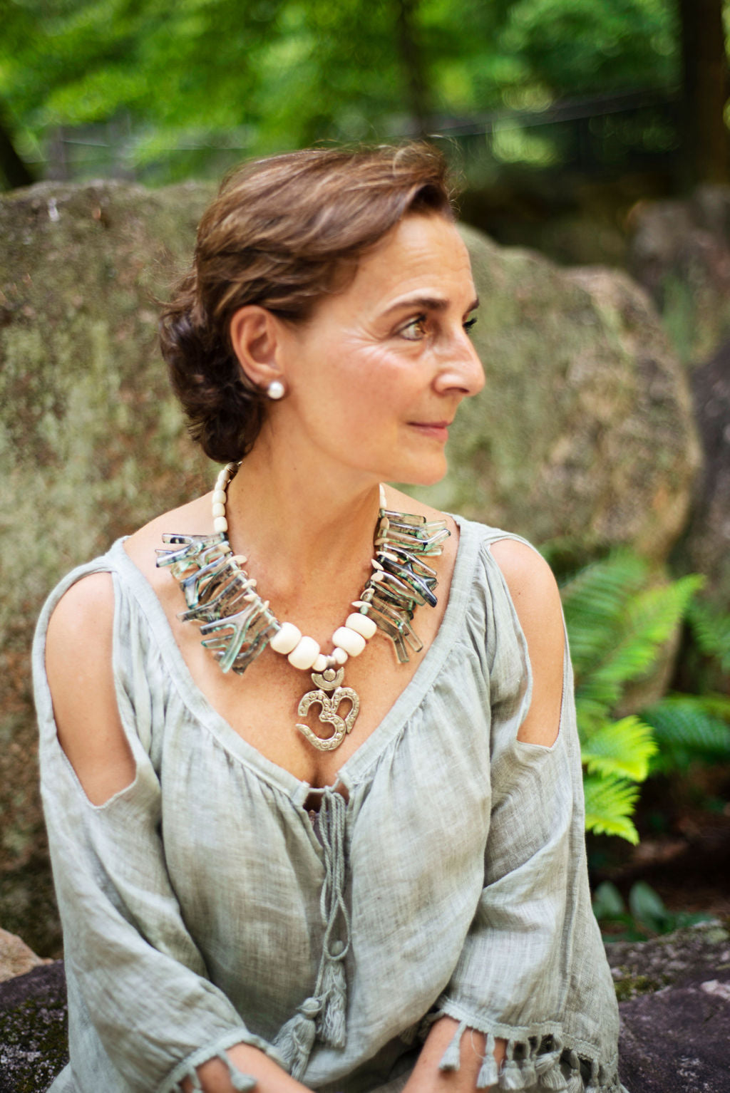 Front view of model wearing a green coral shapes in resin with an Om center piece unique necklace. Cristina Tamames Jewelry Designer