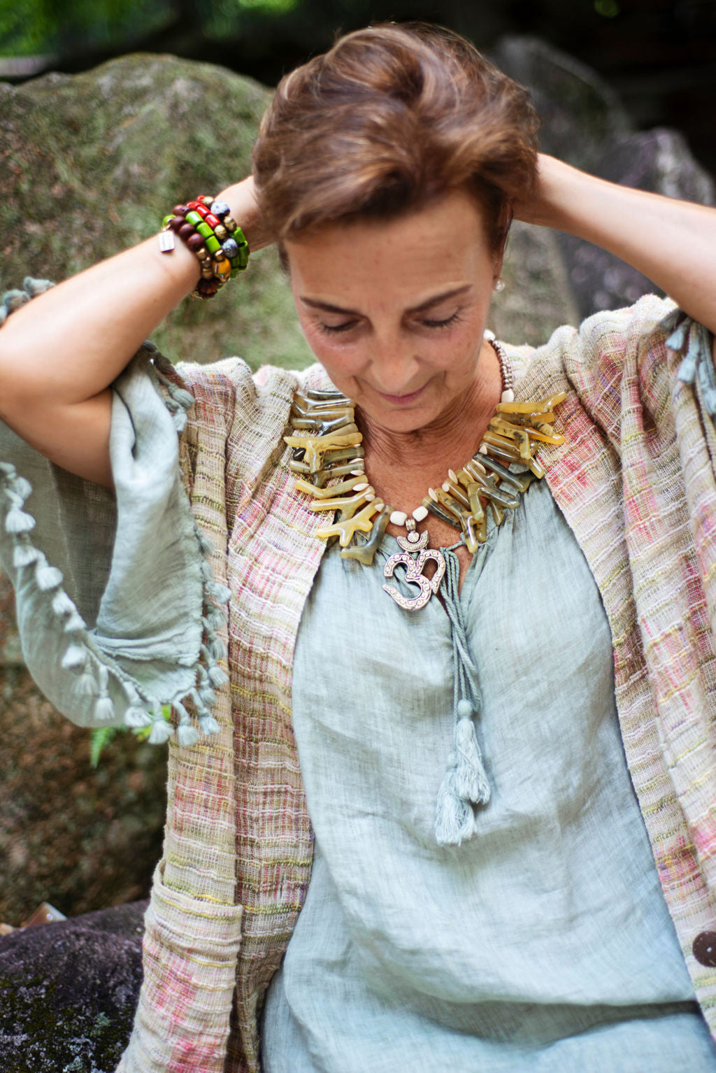 Model wearing a beautiful soft green necklace with coral shapes in resin with Om centerpiece. Cristina Tamames Jewelry Designer