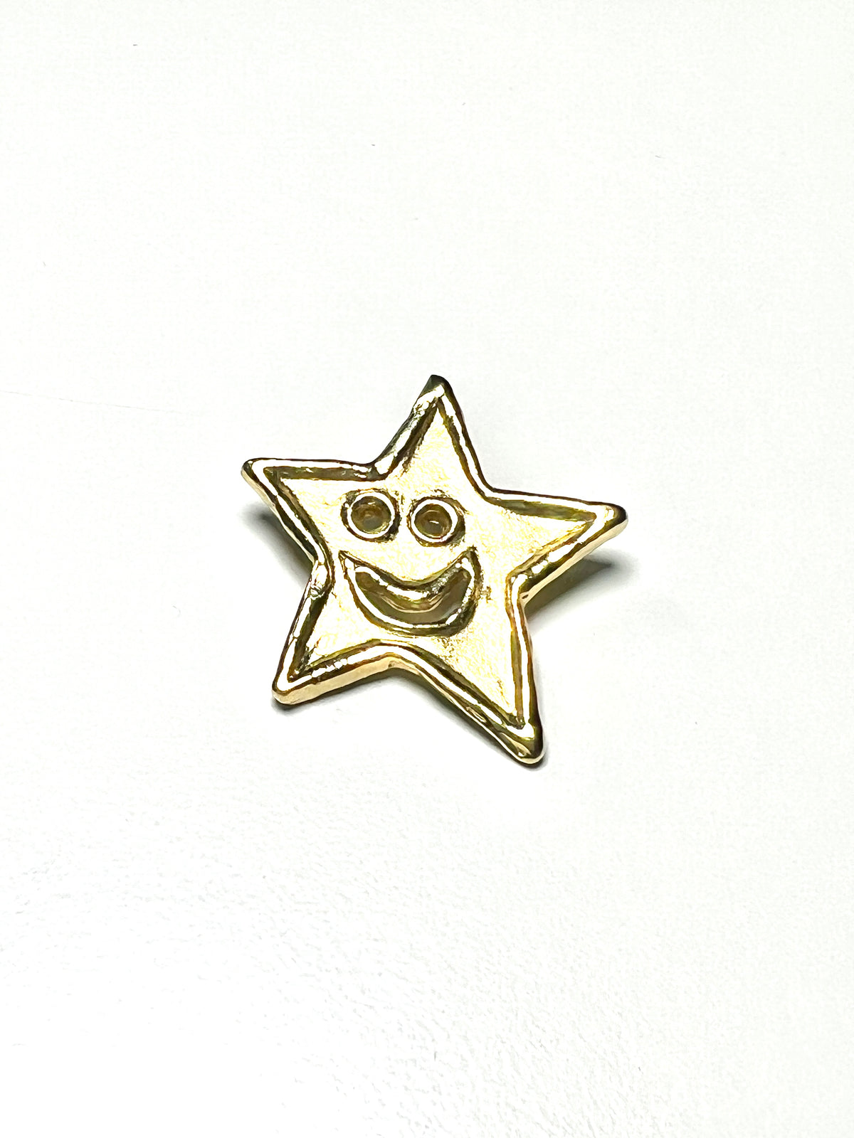 18kt Gold star-shaped pendant with a smiley face on a white background
