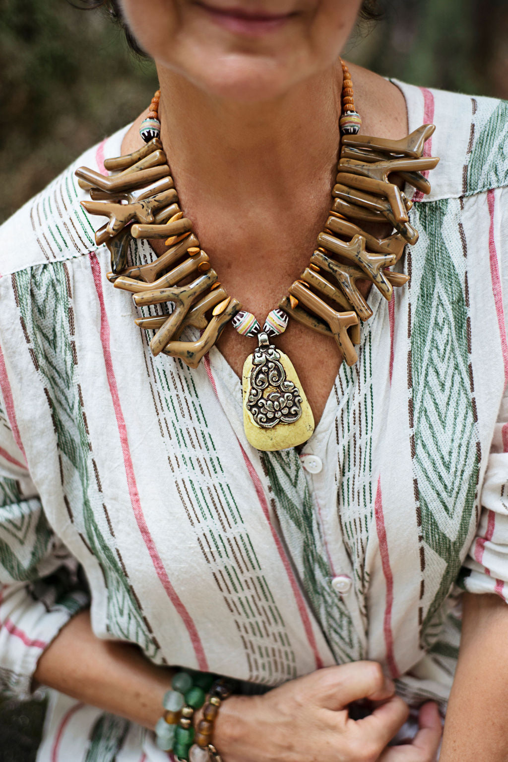 Model wearing a necklace in earthy tones coral shapes of resin with a Nepalese yellow turquoise pendant. Cristina Tamames Jewelry Designer