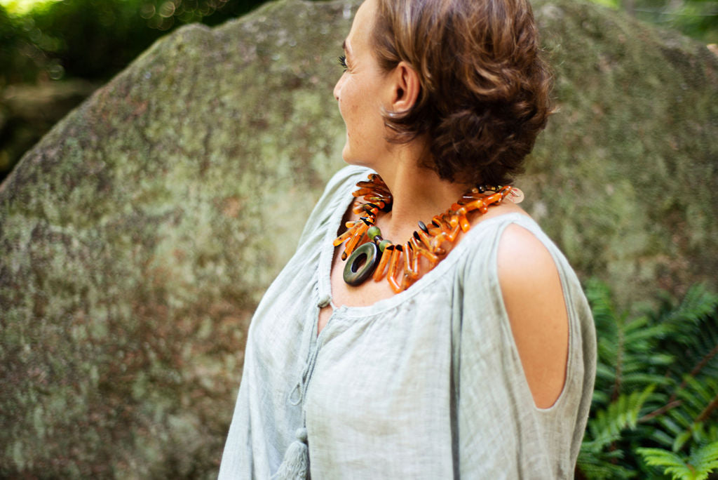 Model wearing a light and easy to wear one of a kind necklace in a beautiful orange tone accented by an ebony big center circle. Cristina Tamames Jewelry Designer