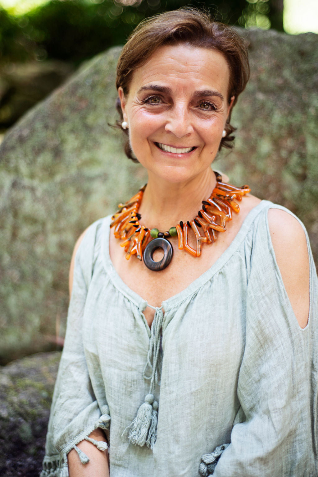 Model wearing a light and easy to wear one of a kind necklace in a beautiful orange tone accented by an ebony big center circle. Cristina Tamames Jewelry Designer