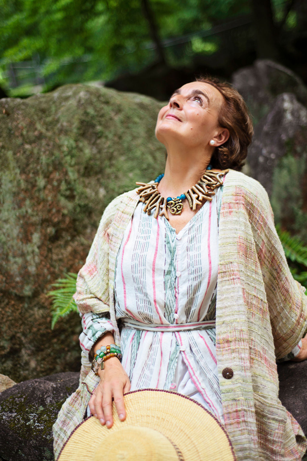 Model wearing earthy tones shapes of resin coral necklace with blue recycled glass African beads and an Om pendant as the center piece. Cristina Tamames Jewelry Designer