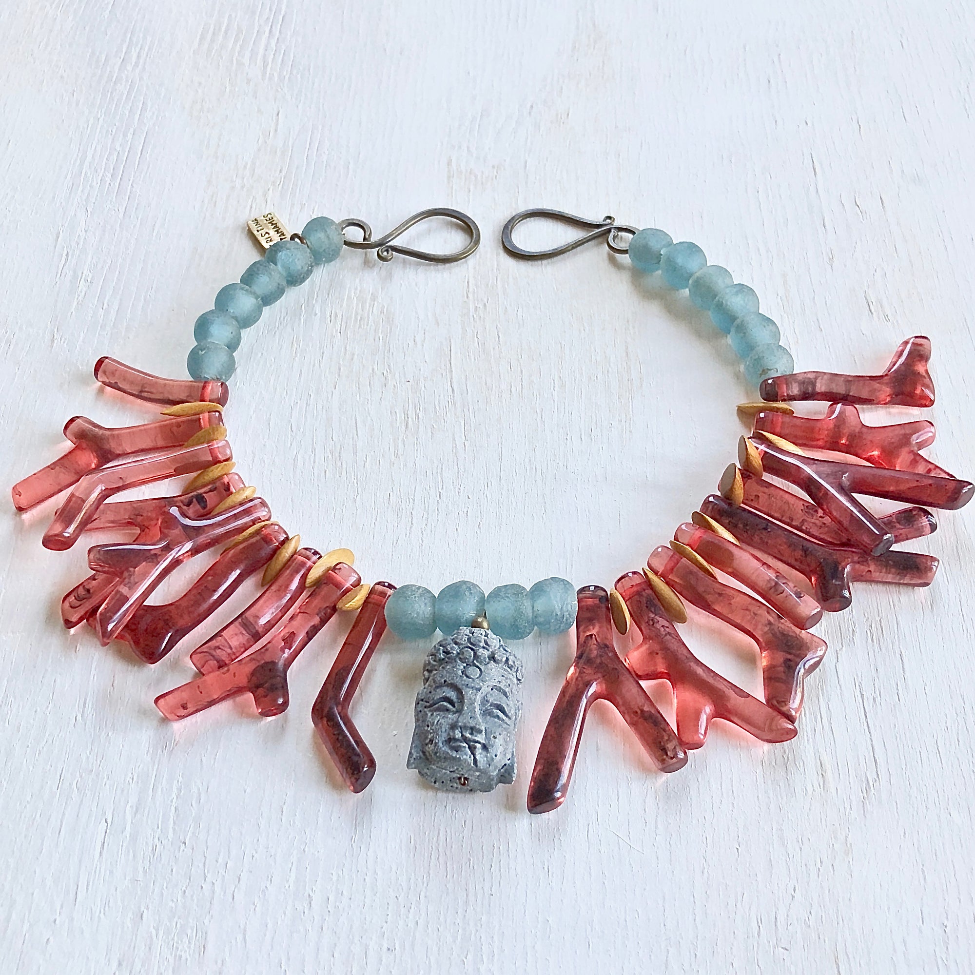 Red shapes of resin coral necklace with blue recycled glass African beads and a Buddha as the center piece. Cristina Tamames Jewelry Designer